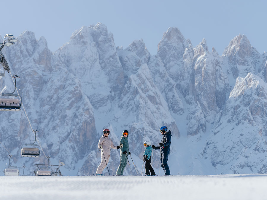 Vier Skifahrer stehen auf einem verschneiten Hang, im Hintergrund sind Berge und Skilifte zu sehen. - Hotel Steinerhof