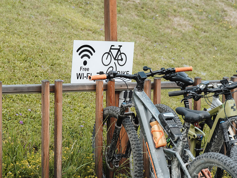 Zwei Fahrräder, die in der Nähe eines Schildes mit der Aufschrift „Free Wi-Fi“ und einem Fahrradsymbol über einer Rasenfläche abgestellt sind. - Hotel Steinerhof