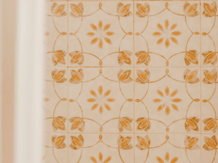 Eine orange-weiß geflieste Wand mit Blumen- und Kreismustern, die auf der linken Seite teilweise verdeckt ist. - Hotel Steinerhof