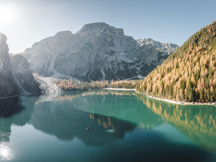 Ein klarer See mit grün-blauem Wasser, umgeben von Bergen und Wald unter einem strahlend blauen Himmel. - Hotel Steinerhof