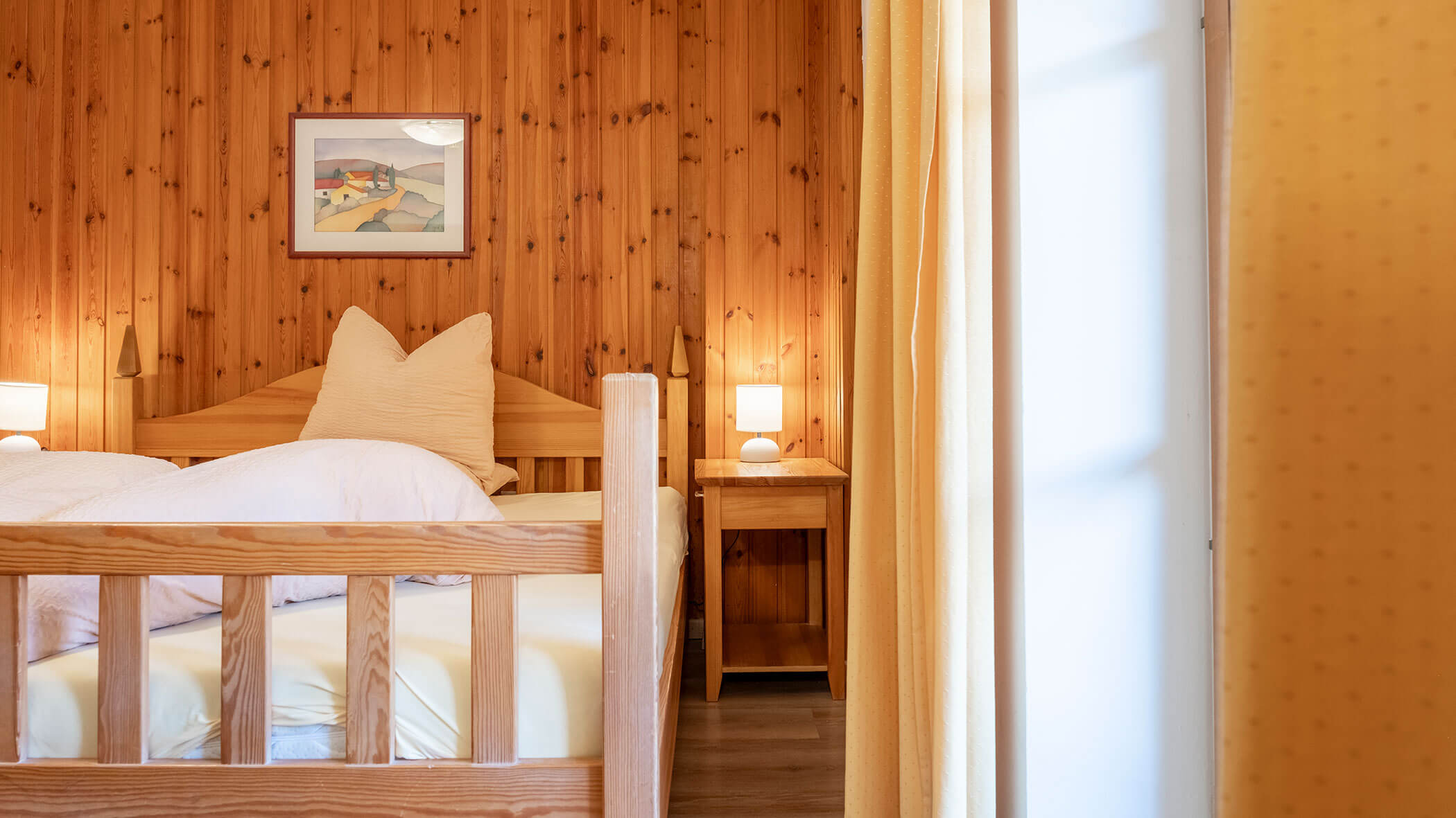 Gemütliches Schlafzimmer aus Holz mit einem Doppelbett, weißer Bettwäsche, Nachttischen, Lampen und einem gerahmten Bild an der Wand. - Hotel Steinerhof