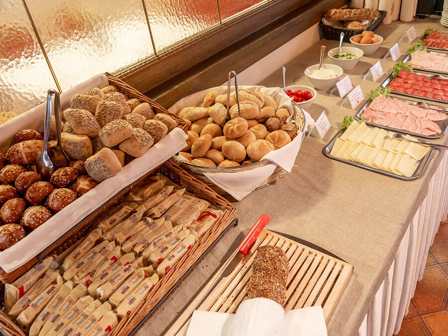 Verschiedene Brotsorten, Käse, Aufschnitt, Butter und Gemüse, auf einem Buffettisch angerichtet. - Hotel Steinerhof